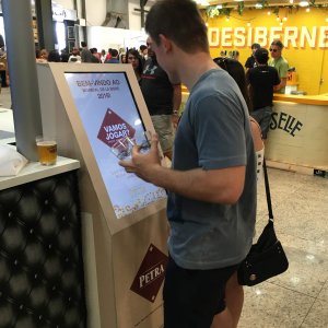 Cliente olhando para game da cerveja Petra na tela de totem