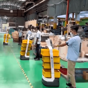 Três robôs Nik auxiliando alguns operadores industriais, com caixas de plástico em suas bandejas